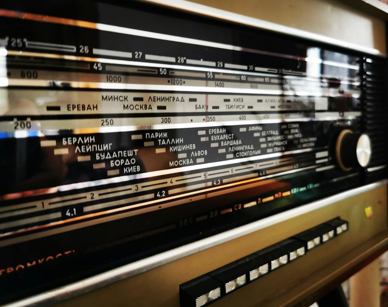 Detailed image of a vintage radio dial featuring city names and frequencies, selective focus.